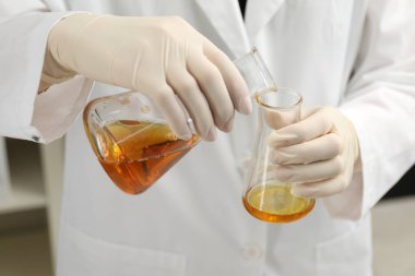 Laboratuvar çalışanı portakal ham petrolü şişeye boşaltıyor.