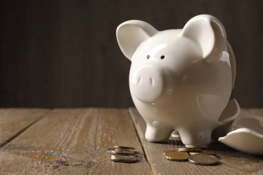 Yoksulluk. Kırık domuz kumbarası ve paralar ahşap masada, metin için yer var.