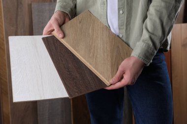 Kapalı alanda ahşap döşeme örnekleri olan bir adam.