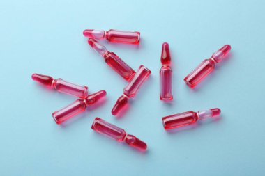 Açık mavi zemin üzerinde sıvı bulunan cam ampuller, üst görünüm