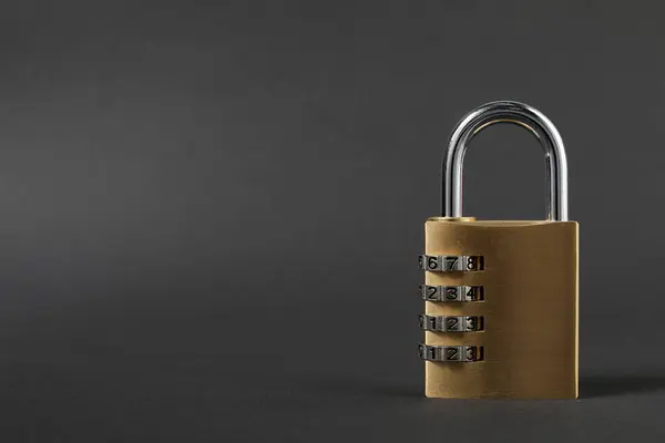 One steel combination padlock on dark grey background, closeup. Space for text