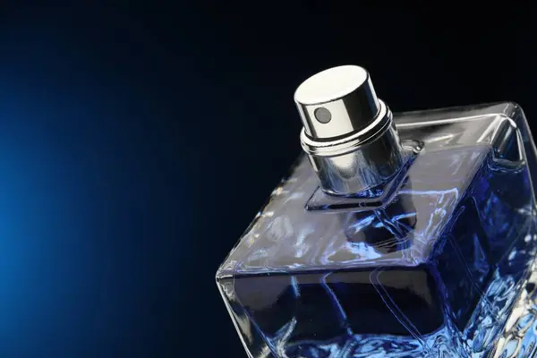 Luxury men`s perfume in bottle against dark blue background, closeup. Space for text