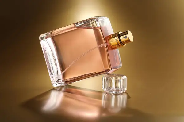 Luxury women\'s perfume. Sunlit glass bottle on golden background