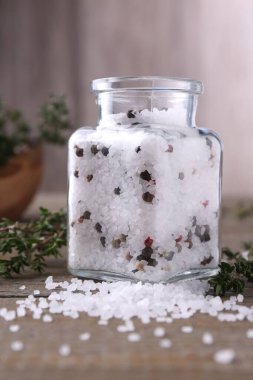 Cam kavanozda biberli tuz ve ahşap masada kekik.