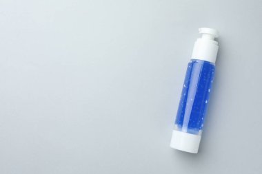 Açık gri arka planda bir şişe kozmetik ürünü, üst görünüm. Metin için boşluk