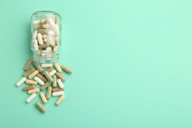 Vitamin hapları ve nane rengi arka planda bir şişe. Metin için boşluk