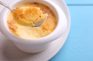 Açık mavi masada kaseden kaşıkla leziz bir creme brulee alıp yakın plan çekiyoruz.