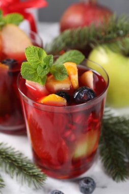 Beyaz mermer masa üzerinde, cam, malzeme ve Noel dekoru içinde Aromatik Sangria içeceği.