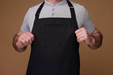 Kahverengi arka planda mutfak önlüğü giyen adam, yakın plan. Tasarım için model