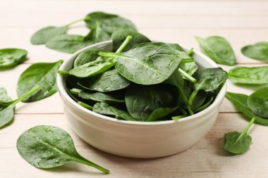 Hafif ahşap masada taze ıspanak yaprakları, yakın plan.