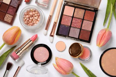 Farklı makyaj ürünleri ve beyaz arka planda güzel lale çiçekleri. Bokeh etkisi