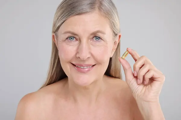 Schöne Frau Mit Vitaminkapsel Auf Grauem Hintergrund — Stockfoto