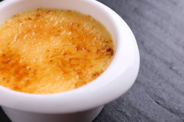 Koyu gri desenli masada, kasede nefis krema brulee, yakın plan.