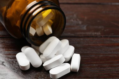 Ahşap masada şişe ve vitamin hapları, yakın plan. Metin için boşluk