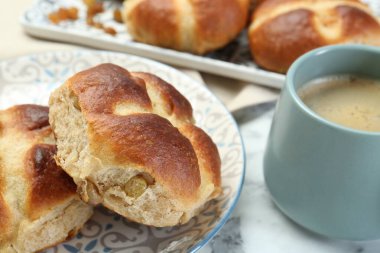 Sıcak haç çörekleri ve beyaz mermer masada kahve, yakın plan.