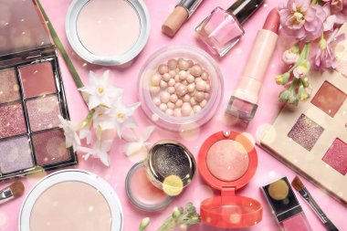 Farklı makyaj ürünleri ve pembe arka planda güzel bahar çiçekleri. Bokeh etkisi