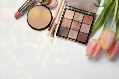 Farklı makyaj ürünleri ve beyaz zemin üzerinde beyaz arkaplan üzerinde güzel bir lale. Bokeh etkisi