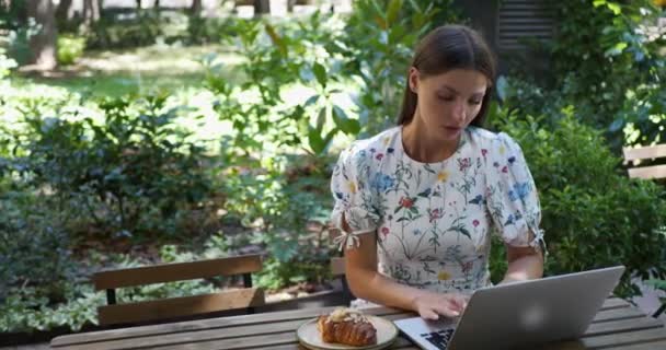 屋外の木のテーブルでラップトップを使用して不幸な女性 — ストック動画