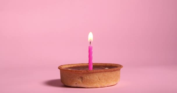 Tartaleta Caramelo Con Vela Festiva Ardiente Sobre Fondo Rosa — Vídeo de stock