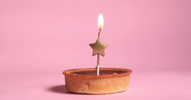 Tartaleta Caramelo Con Vela Festiva Violeta Ardiente Sobre Fondo Rosa — Vídeo de stock