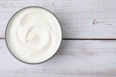 Hafif ahşap masada, tabakta nefis bir yoğurt, üst manzara. Metin için boşluk