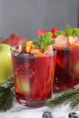 Aromatik Sangria içeceği bardaklarda, malzemelerde ve beyaz mermer masada Noel dekorunda.