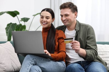Bilgisayarlı ve kredi kartlı mutlu çift evde online alışveriş yapıyor.