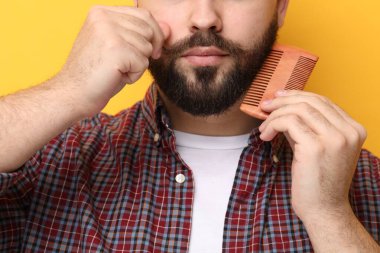 Yakışıklı genç adam sarı arka planda sakal tarıyor, yakın plan.