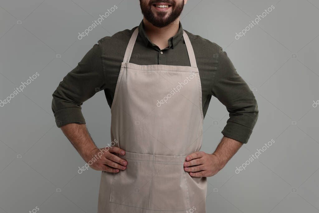Smiling man in kitchen apron on grey background, closeup. Mockup for design