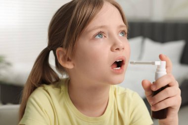 Evde boğaz spreyi kullanan küçük kız.