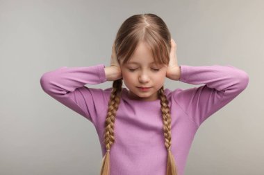 İşitme problemi. Gri arka planda kulak ağrısı çeken küçük bir kız.
