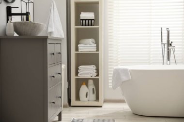 Şık bir banyo. Gri çekmeceler ve raf ünitesi var.