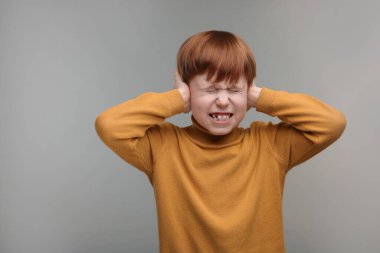 İşitme problemi. Küçük çocuk gri arka planda kulak ağrısından muzdarip, mesaj için boşluk
