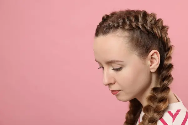 Woman with braided hair on pink background, space for text