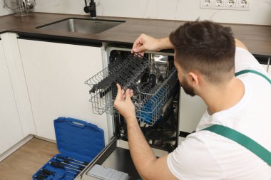 Mutfaktaki bulaşık makinesini inceleyen servis elemanı.
