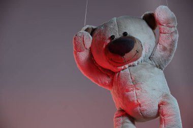 Gri arka planda, renkli ışıklar içinde sevimli bir oyuncak ayı. Metin için boşluk