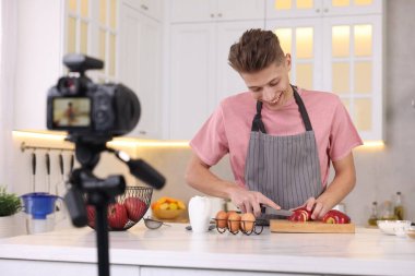 Mutfakta video kaydederken gülümseyen yemek blogcusu yemek pişiriyor