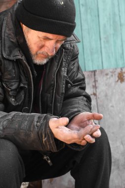 Zavallı evsiz yaşlı adam dışarıda bozuk para tutuyor.