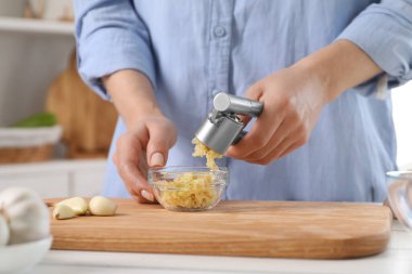 Mutfaktaki beyaz masada basın mensuplarıyla sarımsak sıkan kadın, yakın plan.