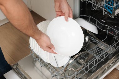Bulaşık makinesini tabaklarla dolduran adam, yakın plan.