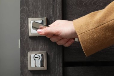 Kapıda ahşap kapı açan kadın, kapı koluna yakın çekim.