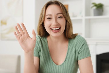 Evdeki görüntülü sohbet sırasında el sallayan genç kadın, webcam 'den görüntü