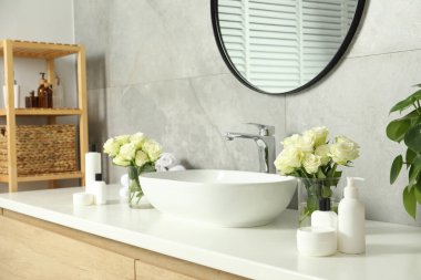 Güzel güller ve banyo aksesuarları banyoda lavabonun yanında.