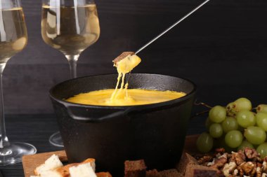 Erimiş peynirle fondü tenceresine ekmek daldırmak, yakın plan.