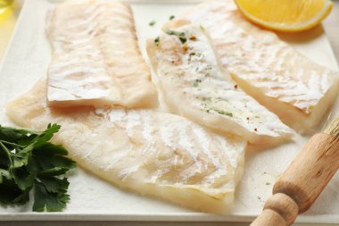 Baharatlı taze morina filetosu ve tabakta fırça, yakın plan.