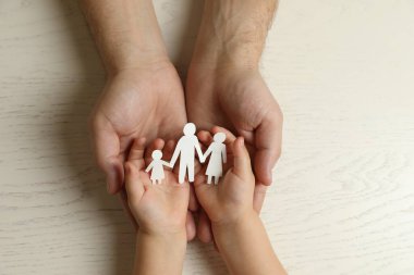 Baba ve çocuk ellerinde kağıt parçalarıyla beyaz ahşap masada, üst tarafta.