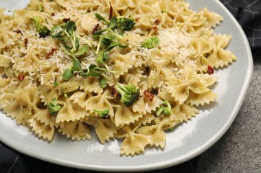 Vejetaryen yemeği. Gri masada taze sebzeli ve peynirli lezzetli makarna, yakın plan.