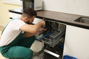 Mutfaktaki bulaşık makinesini inceleyen servis elemanı.
