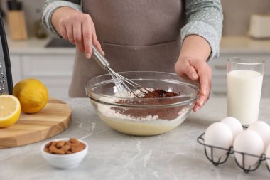 Çikolata hamuru yapan kadın gri mermer masada çırpıcıyla, yakın plan.