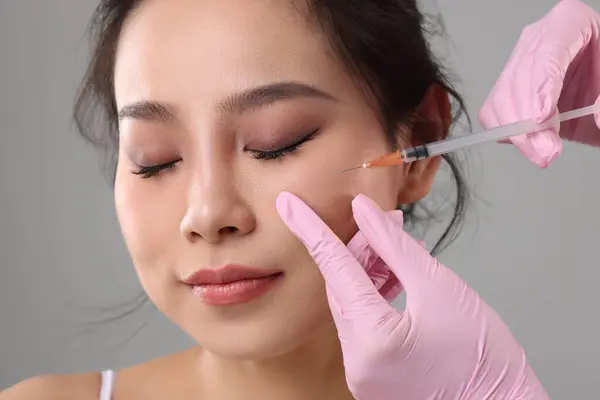 stock image Woman getting facial injection on grey background, closeup